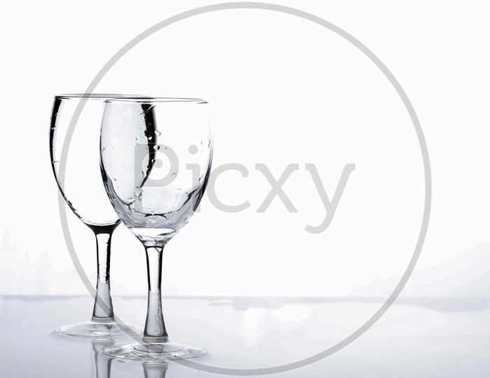 Wine Glasses Filled With Water and Water Splash On an Isolated White Background