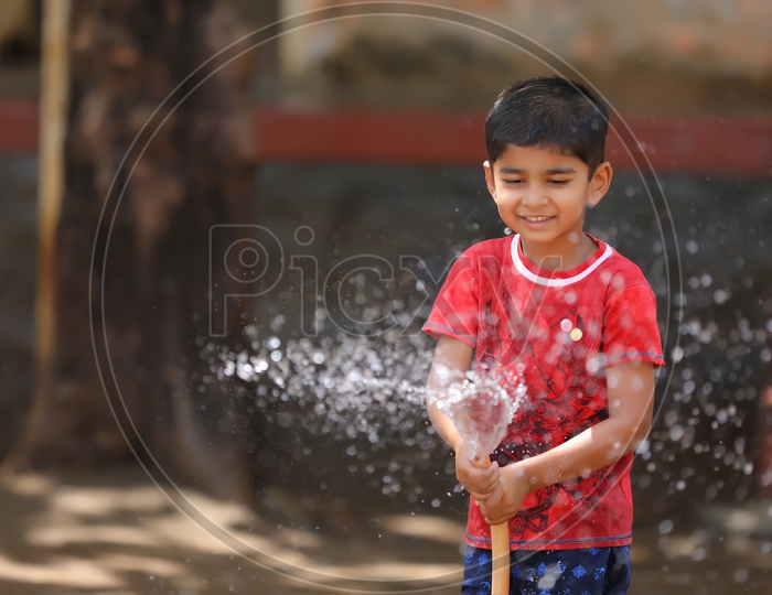 Indian Young Kid Or Child  Playing With Water Tube Water Splash