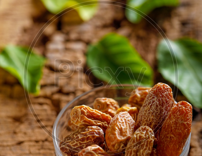 Dried Dates in a Bowl  Dry Raw Organic  Medjool Date Fruit with Green Leafs On an Old Wood  Table Background