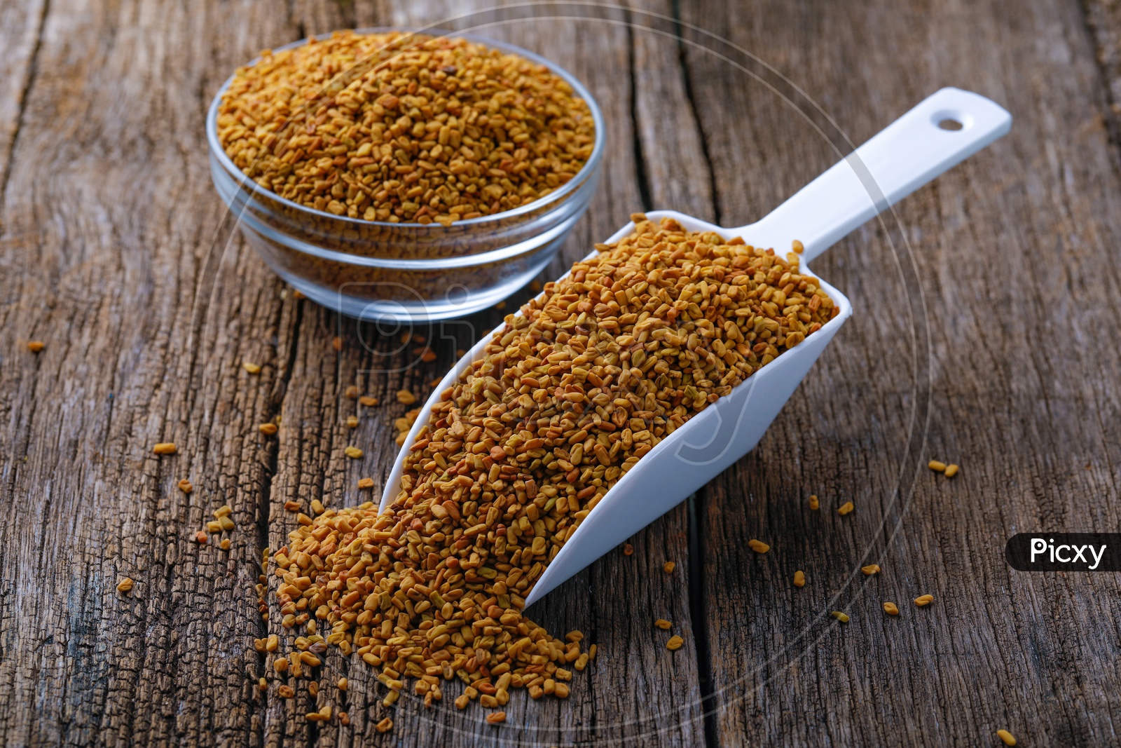 Fenugreek Seeds In a Glass Bowl  and In Scoop On an Wooden Background