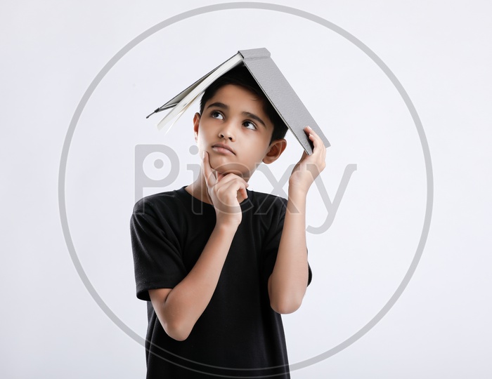 Indian or Asian Boy or Kid O r Child  Keeping Book On Head   over an Isolated White Background