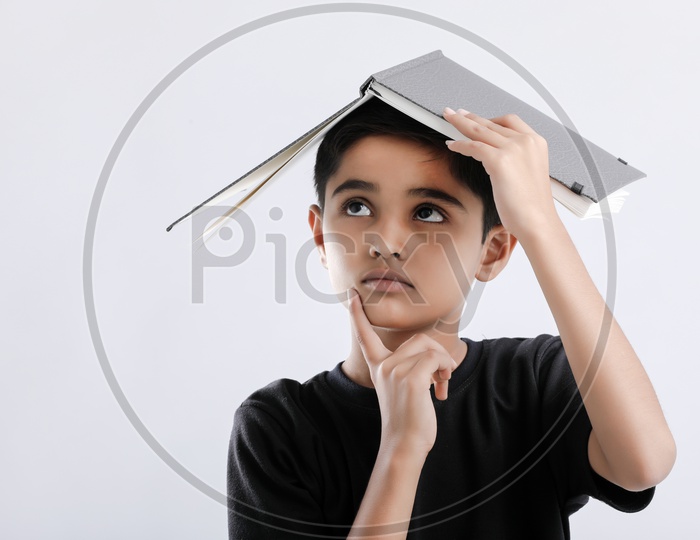 Indian or Asian Boy or Kid O r Child  Keeping Book On Head   over an Isolated White Background