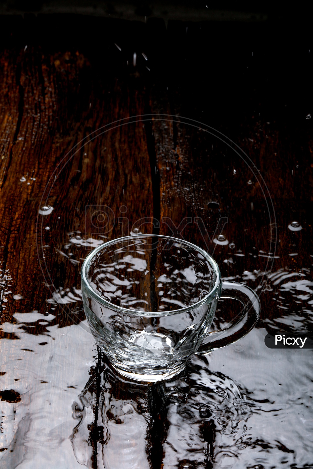 Water Filled In an Glass Tea Cup and Water Splash On an Wooden Table