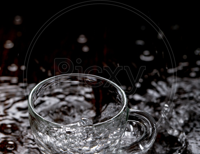 Empty Glass  Tea Cup Filling  With Water And Water Splash On an Wooden  Table Background