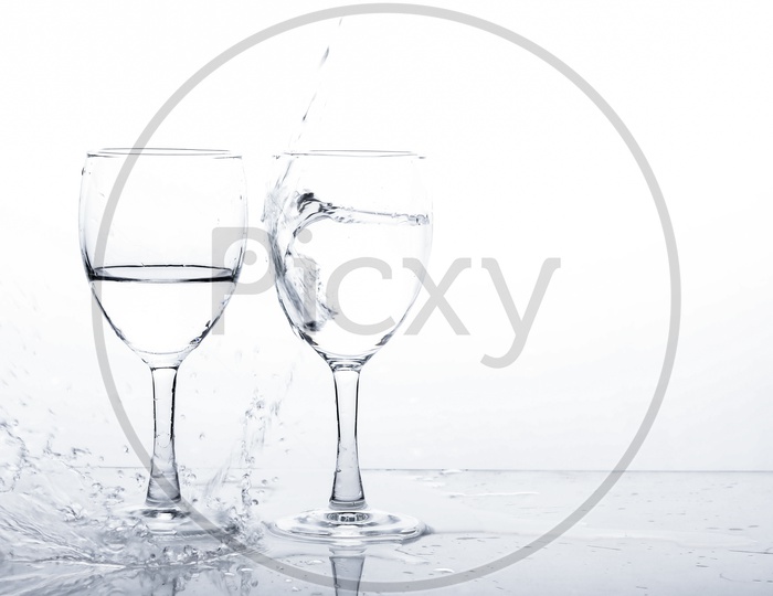 Empty Wine Glasses Filled With Water and Water Splash  On an Isolated White Background
