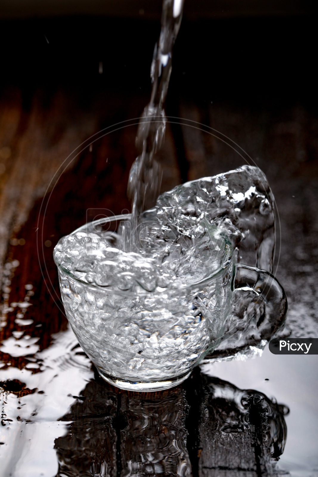 Glass Tea Cup Filling With Water With Water Splash On an Wooden Background