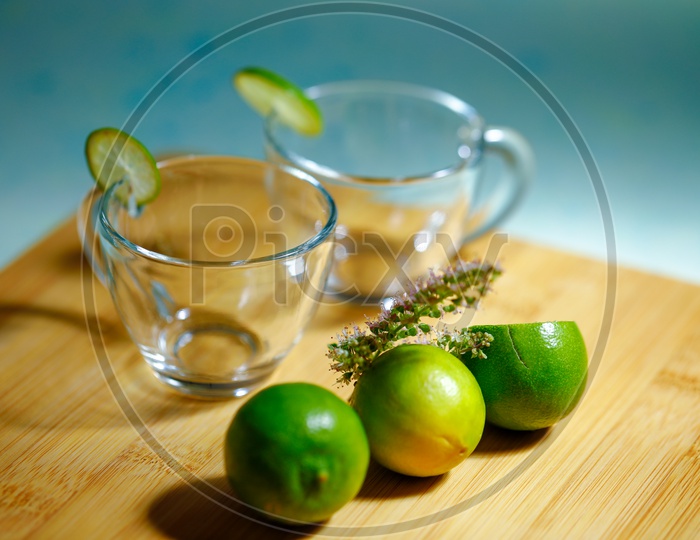 Empty Glass Tea Cups With Lemons And Holi Basil On Wooden  Table