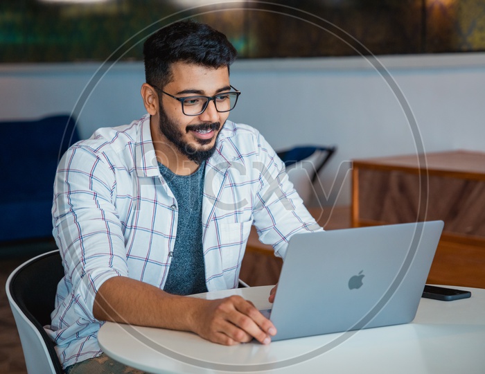 Young man or Indian man or Student Happily Smiling Using Laptop in Office Working Space