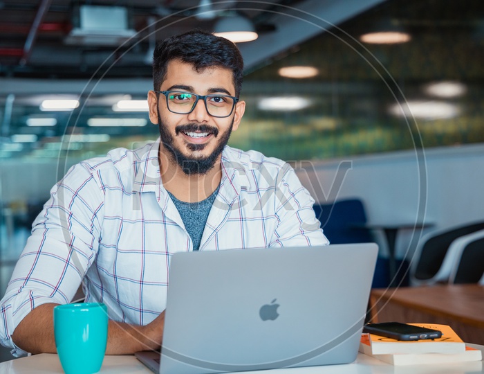 Young man or Indian man Happily Smiling Using Laptop in Office Working Space