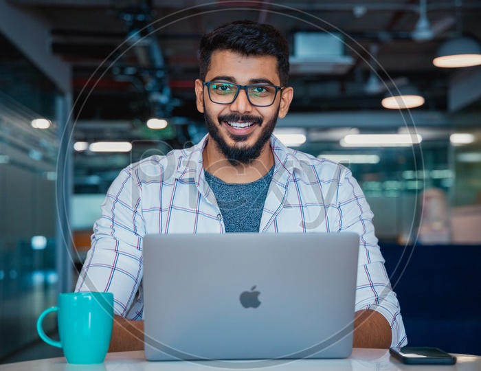 Young man or Indian man or Student Happily Smiling Using Laptop in Office Working Space