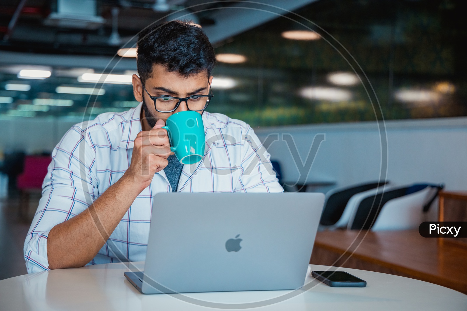 Stressed Tired  Indian professional Young  Man  Having Coffee While Working On Laptop  at Work Space