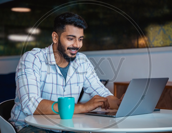 Young man or Indian man Happily Smiling Using Laptop in Office Working Space