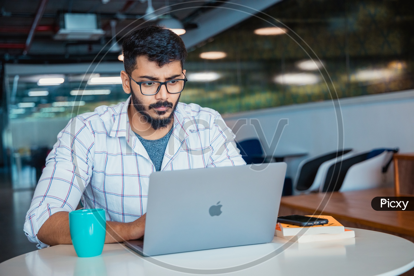 Focused Serious Working Indian Professional IT Employee Young Man  On Laptop In Office Work Space
