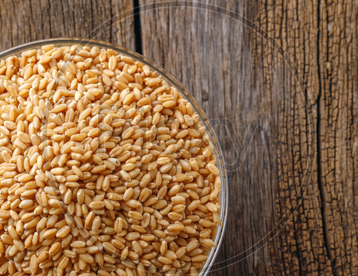 Wheat Grains In a  Glass Bowl On an Isolated Wooden Background