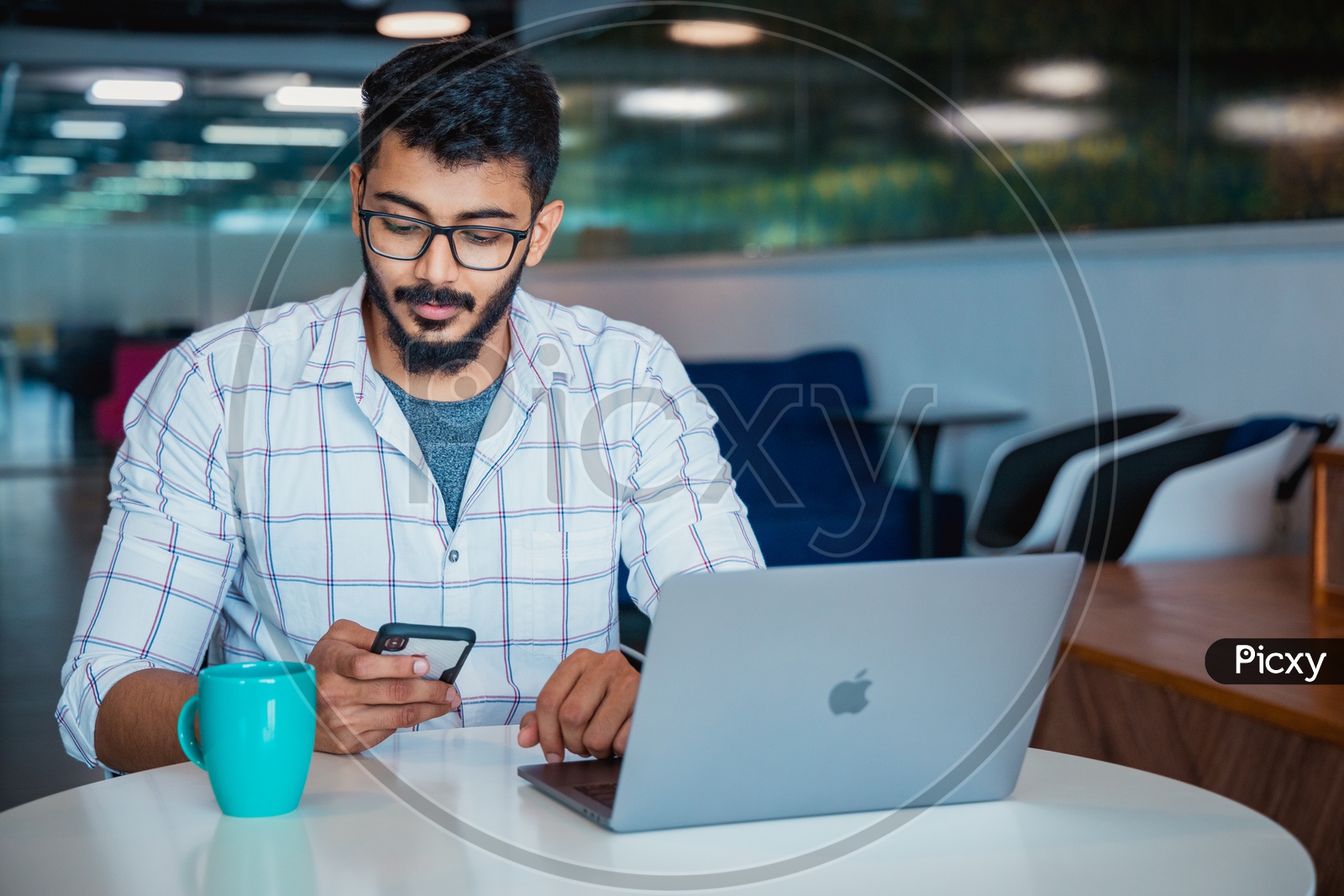 Young Man Or Indian Man or Student Using  Mobile Or Smartphone  At Work Space With Laptop on Desk