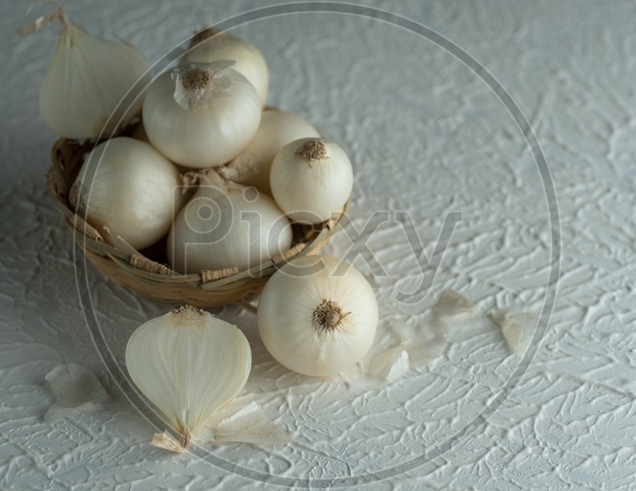 Onions Or White Onions in a Wooden Weaved Bowlon a Textured Background