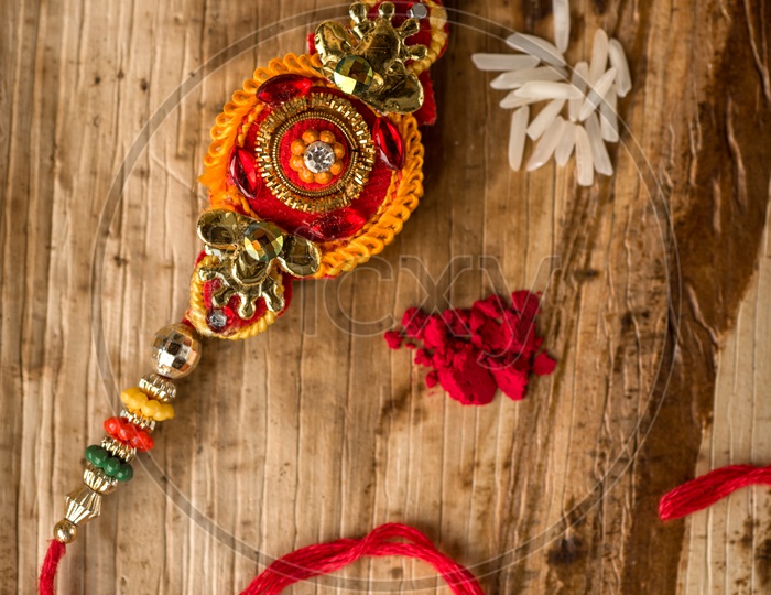 Raksha Bandhan  Traditional Rakhi  with kumkum  and rice grains on an  Textured  Background