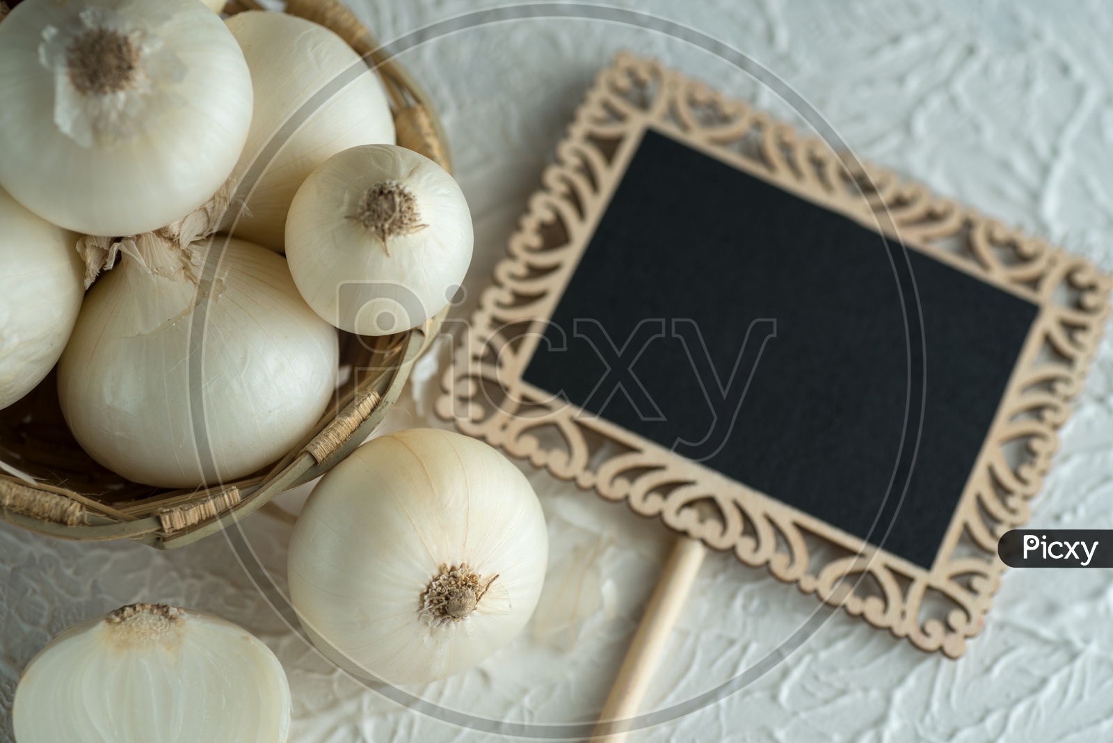 Onions Or White Onions in a Wooden Weaved Bowl with Small Black Board on a Textured Background Food Ingredients