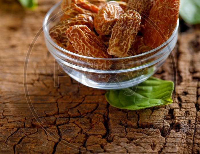 Dried Dates in a Bowl  Dry Raw Organic  Medjool Date Fruit with Green Leafs On an Old Wood  Table Background