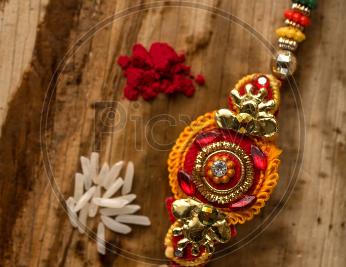 Raksha Bandhan  Traditional Rakhi  with kumkum  and rice grains on an  Textured  Background