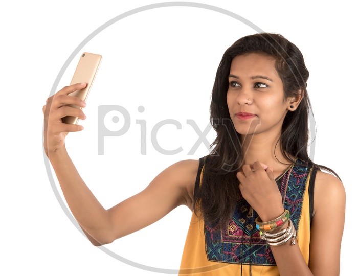 Young Indian Girl Taking Selfie With Mobile Or Smartphone  On an Isolated White Background