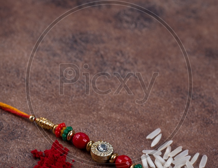 Raksha Bandhan  Traditional Rakhi  with kumkum  and rice grains on an  Textured  Stone  Background