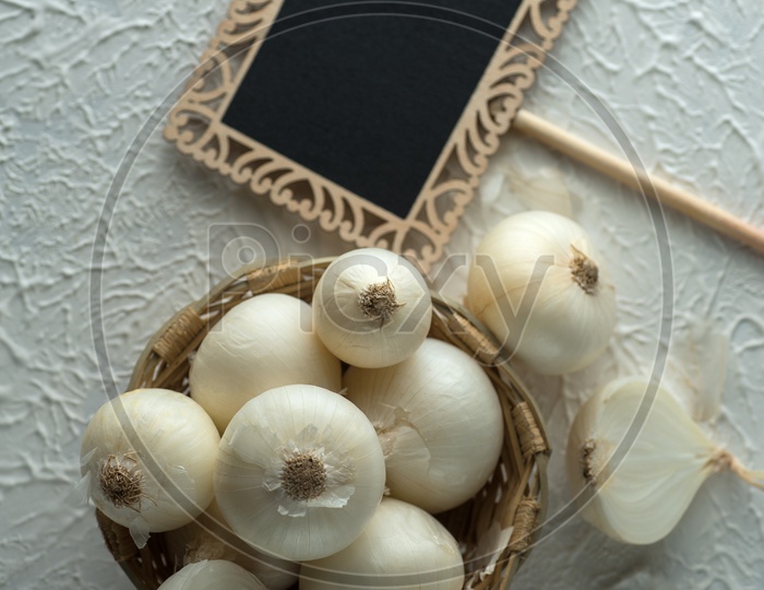 Onions Or White Onions in a Wooden Weaved Bowl with Small Black Board on a Textured Background Food Ingredients