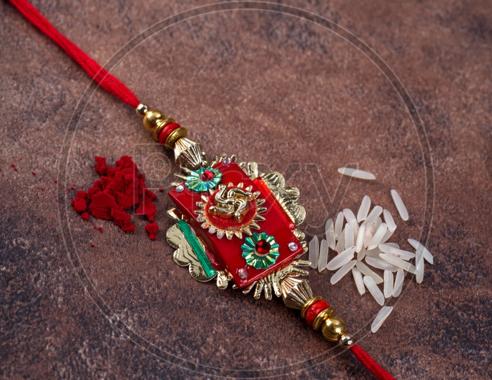 Raksha Bandhan  Traditional Rakhi  with kumkum  and rice grains on an  Textured  Stone  Background