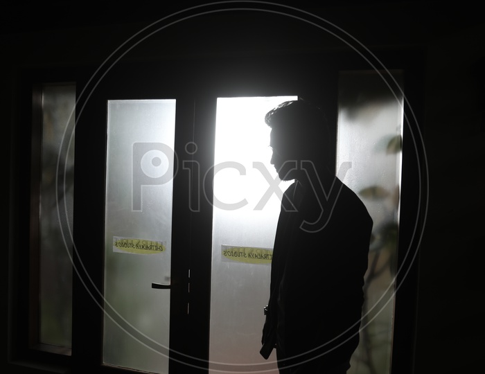 Silhouette Of a Young Man Over a Light From a Glass Shield