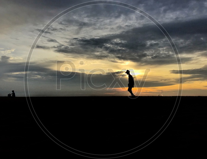 Silhouette Of A Man Walking Over Sunset Sky