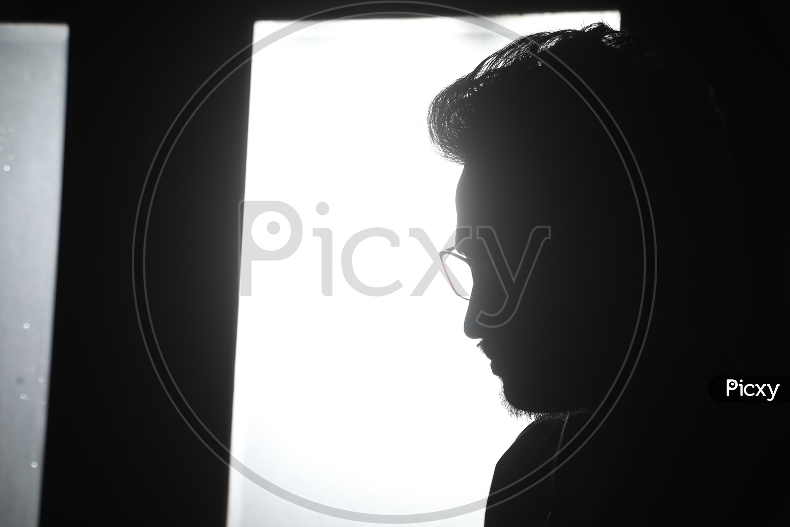 Silhouette Of a Young Man Over a Light From a Glass Shield