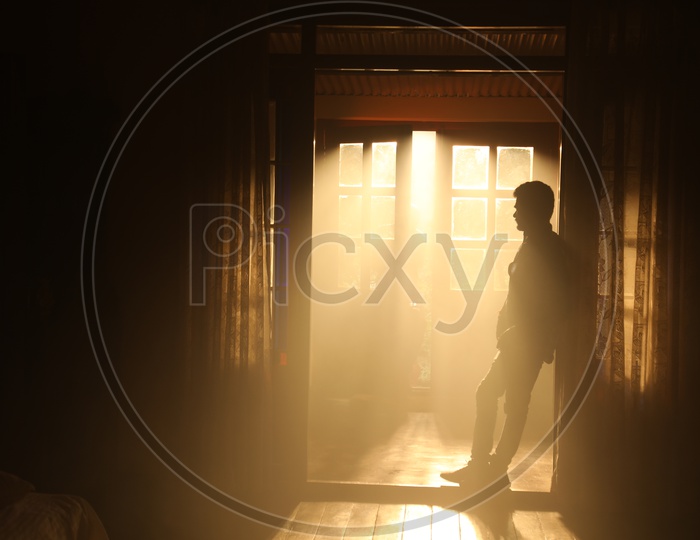 Silhouette Of a Man Over a Light Through a House Door