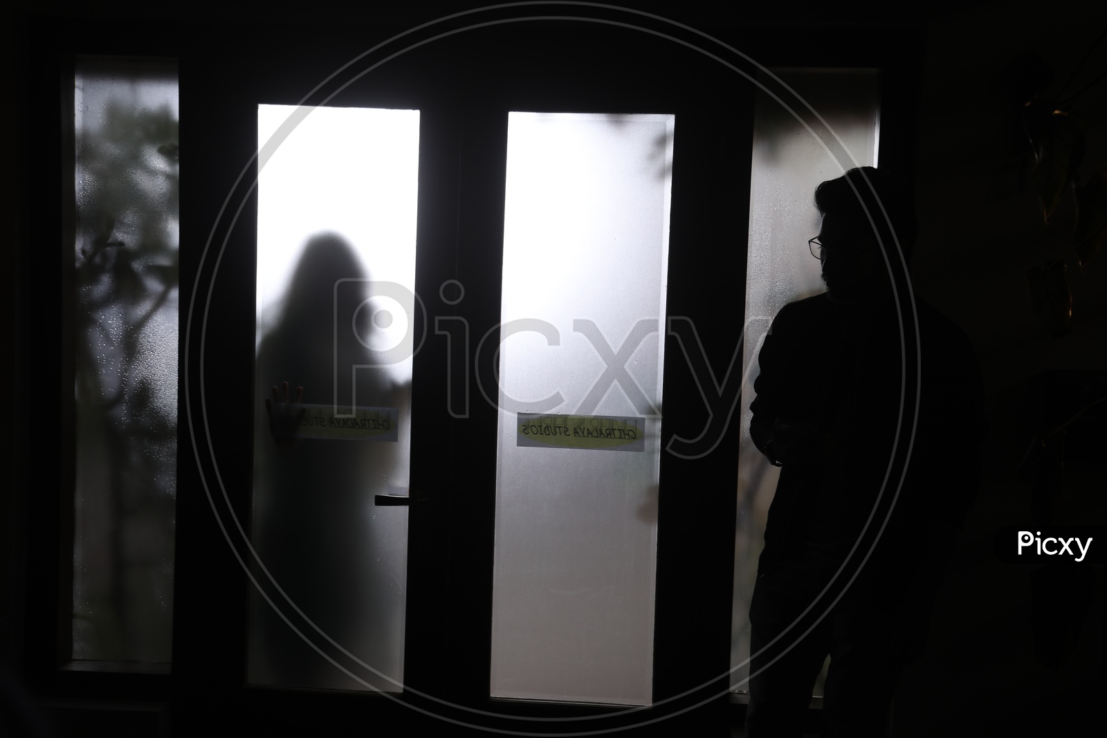 Silhouette Of a Man And Woman With a Glass Shield between Them
