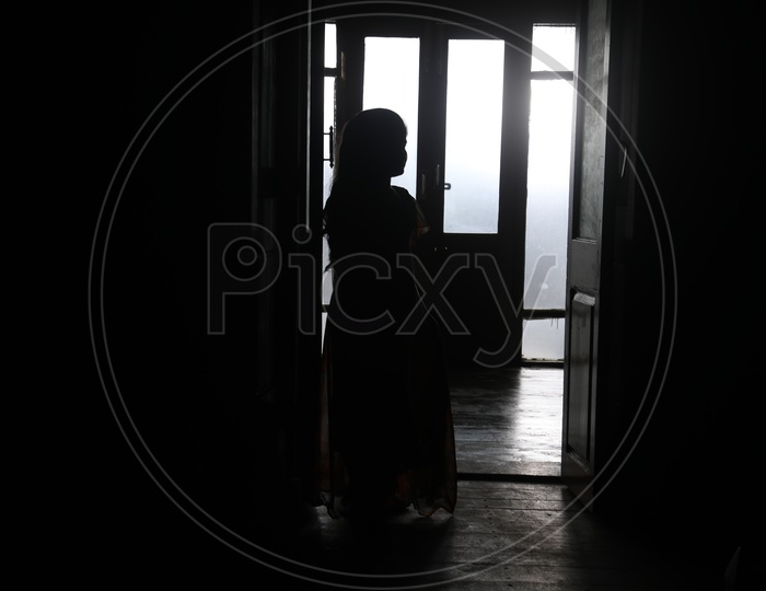 Silhouette of a Girl Child On a House Over Sunlight Through Windows