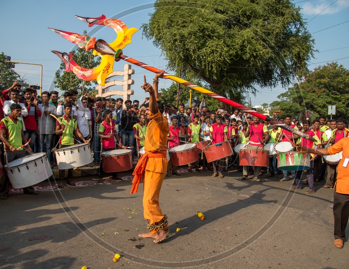 A Man Performing With heavy Thrisul or trident  on roads before Crowd Of People During Ganesh Chaturdhi Festival Procession