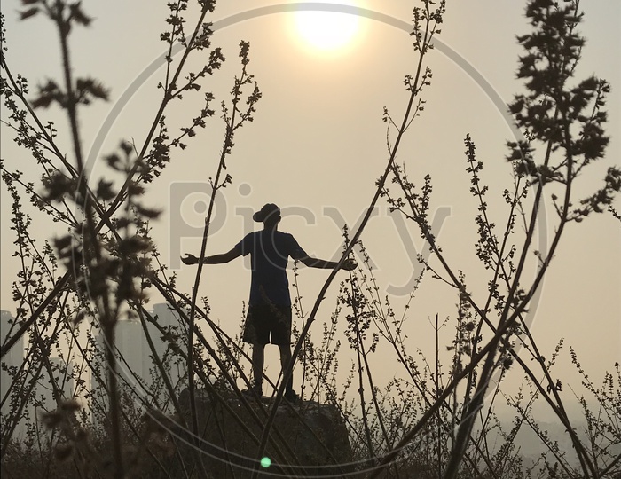A Man Standing Alone And Feeling The Nature With a Sun in The Sky Background