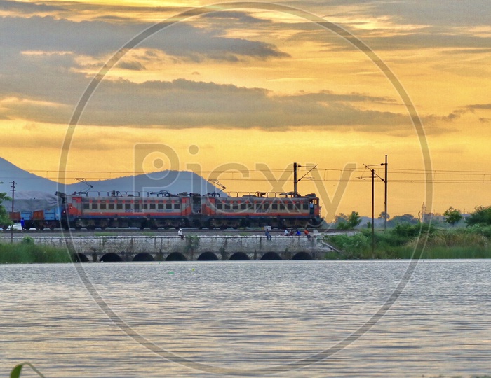 Lakeside View With a train On Track And Sunset Sky in Background