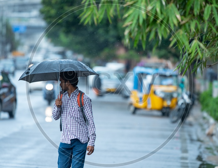Pedestrains Taking Shiled From Monsoon Drizzle with Umbrellas on Hi-tech City Roads