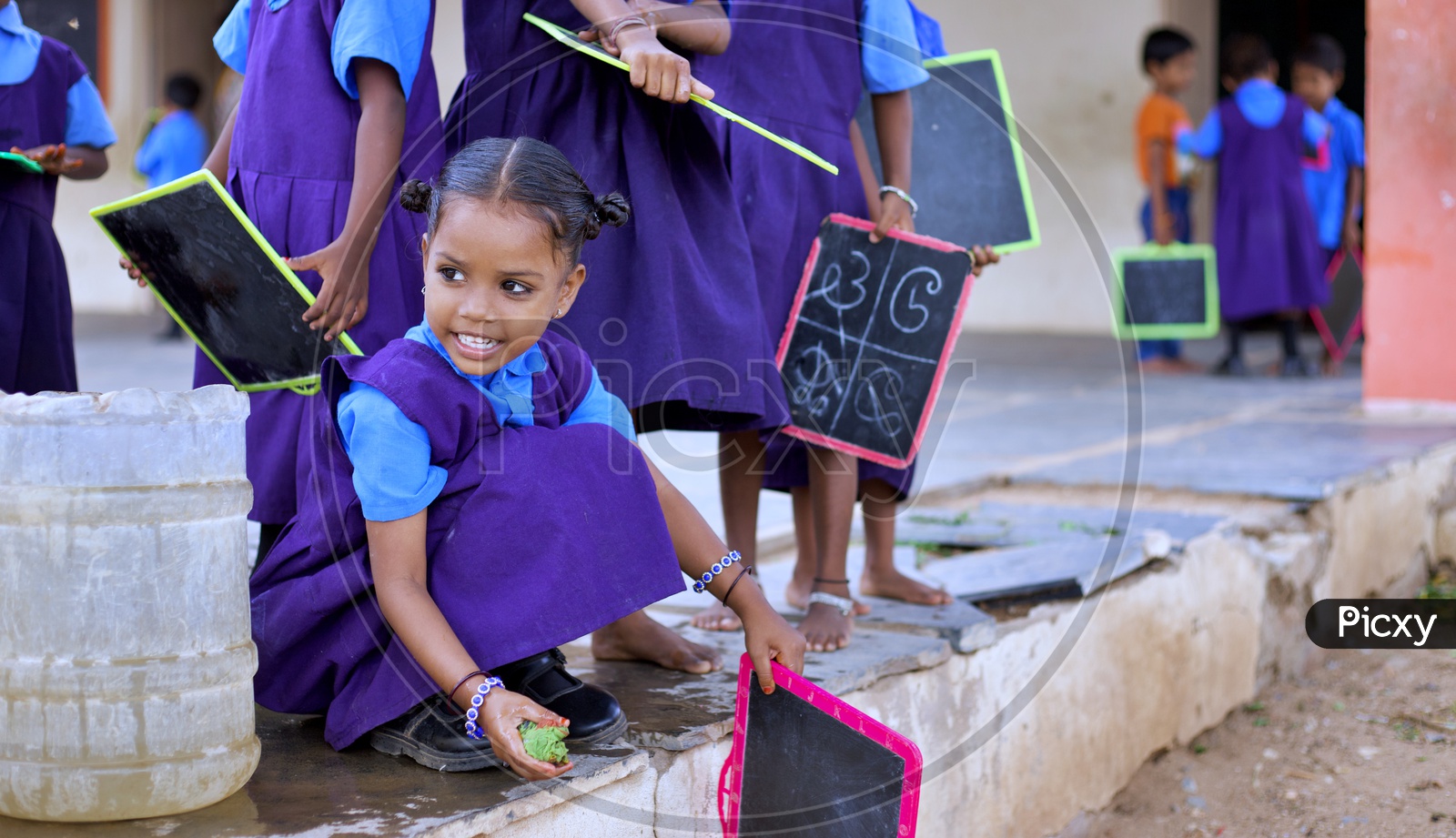 A Govt school girl student washing her slate.