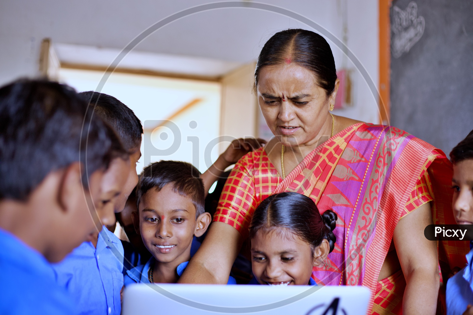 A Govt teacher showing lessons on a laptop.