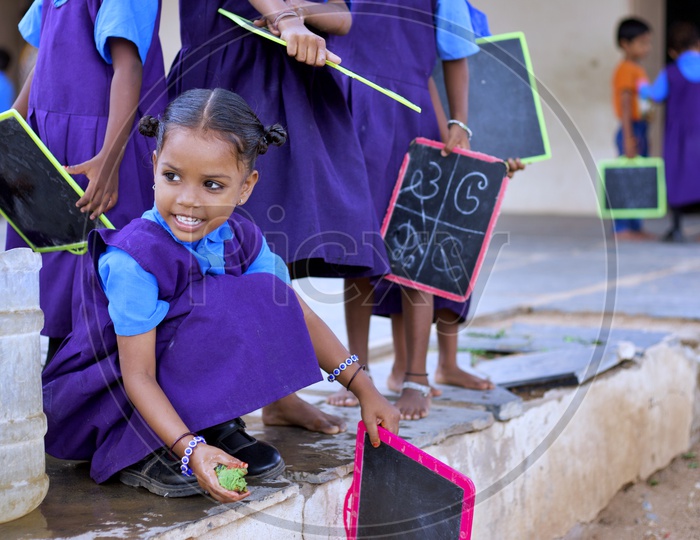 A Govt school girl student washing her slate.