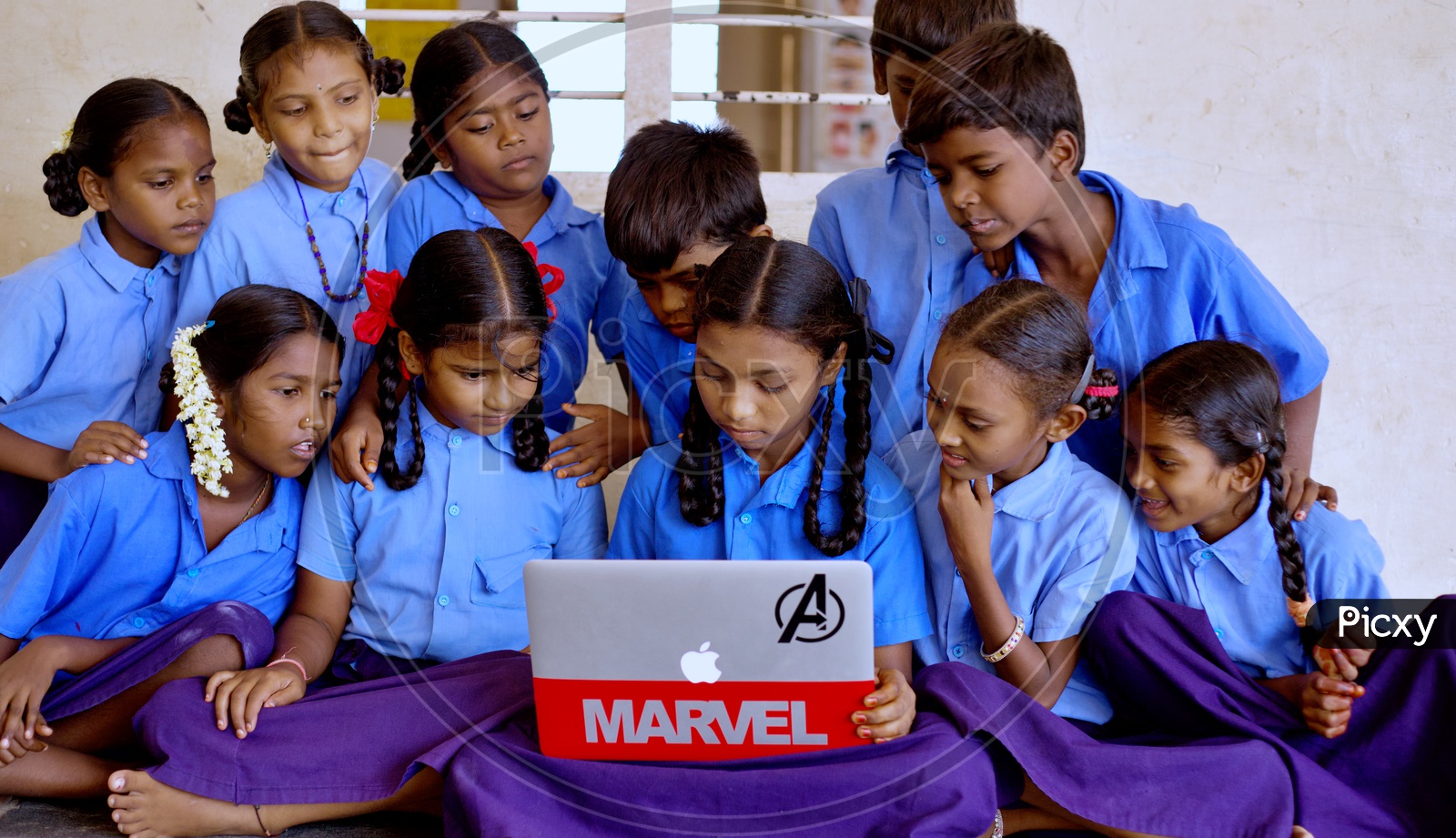 Govt school students watching at a laptop.