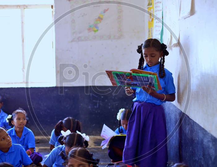 A girl student reading lessons in a classroom.