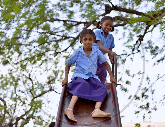 Girl students playing on a slide.