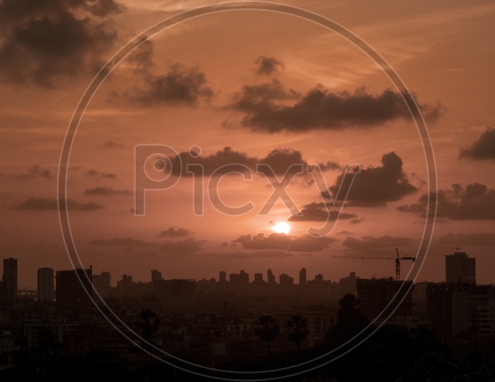 A View Of Sunset over City Scape With Dark Clouds In Sky