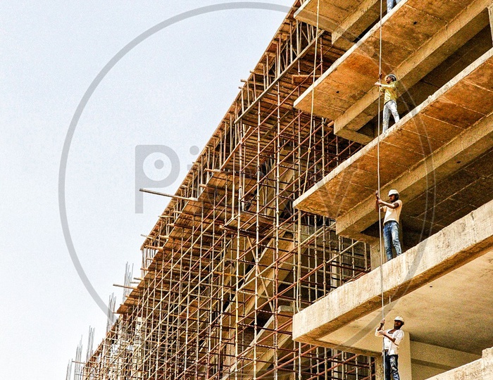 Team Work Of Construction Workers Carrying A Long Iron Bar