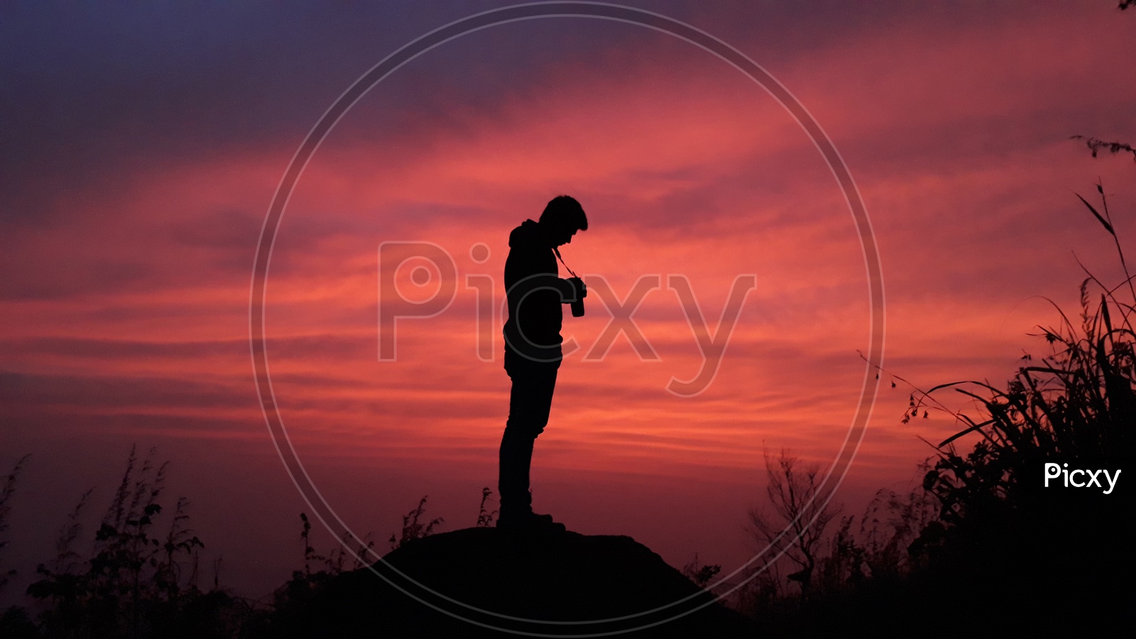 Man with his camera on the top of a hill