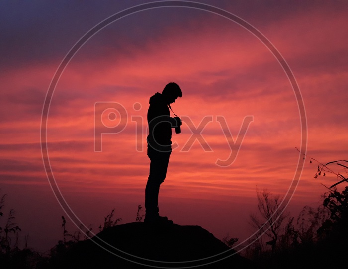 Man using his camera on the top of the hill