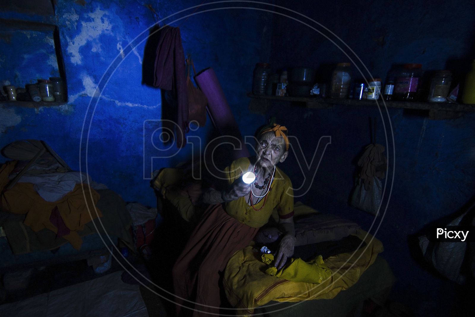 An old lady searches for her medicines with a help of a torch during a sudden power cut in a old age home of Varanasi