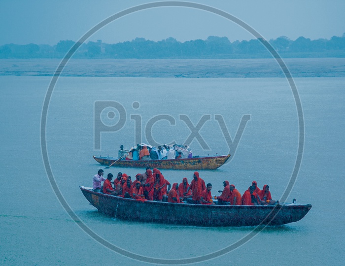 People covering them when it's raining while have a boat ride in river Ganga
